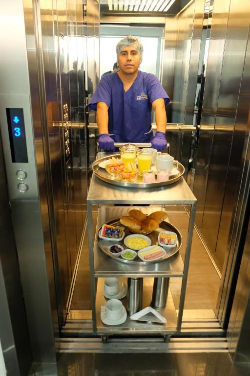 a man standing in a elevator with a tray of food at Hotel Puma'r Tacna in Tacna