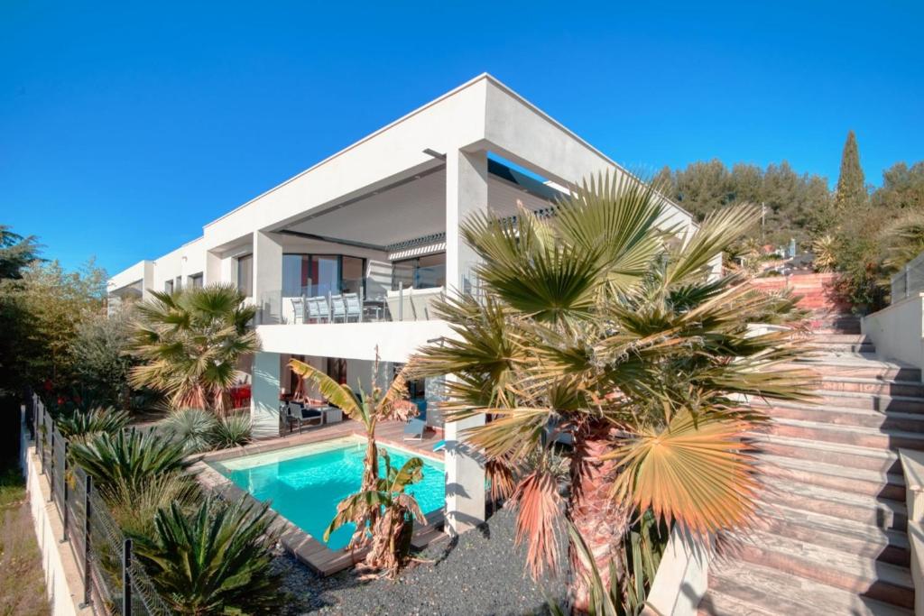 a house with a swimming pool and palm trees at Prestigious villa with panoramic sea view in Bandol