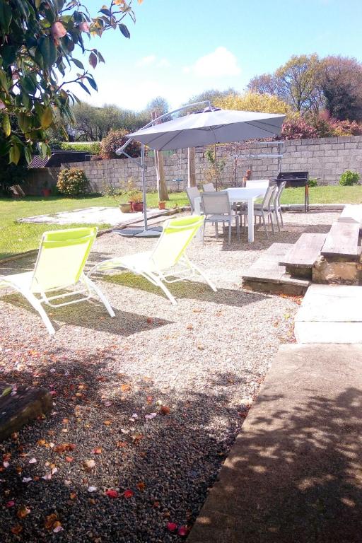 2 chaises jaunes, une table et un parasol dans l'établissement Les Camélias, à Loctudy