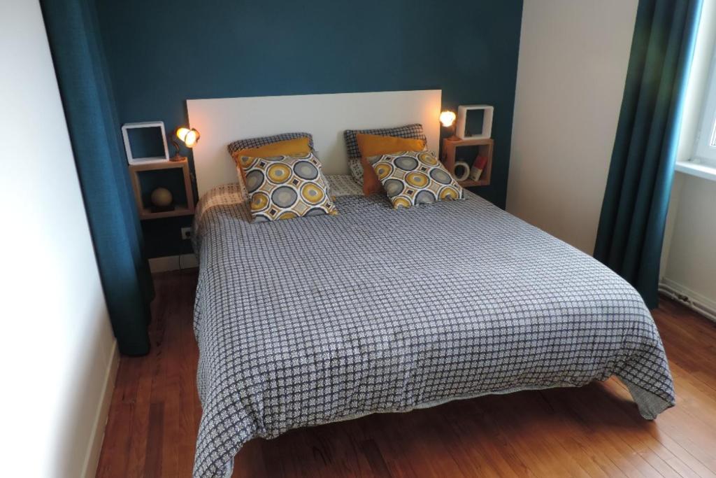 een slaapkamer met een bed met een geruite deken en kussens bij Les Camélias in Loctudy