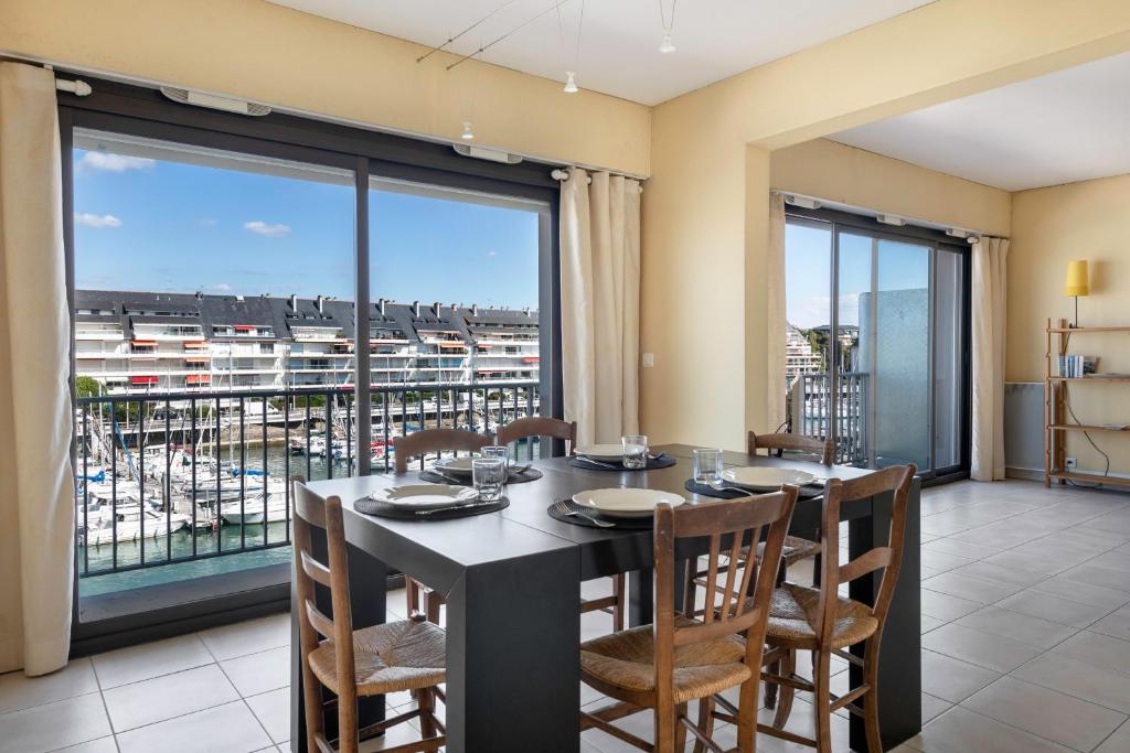 een eetkamer met een tafel en stoelen en een groot raam bij Face au port, appartement pour 4 personnes in Le Pouliguen