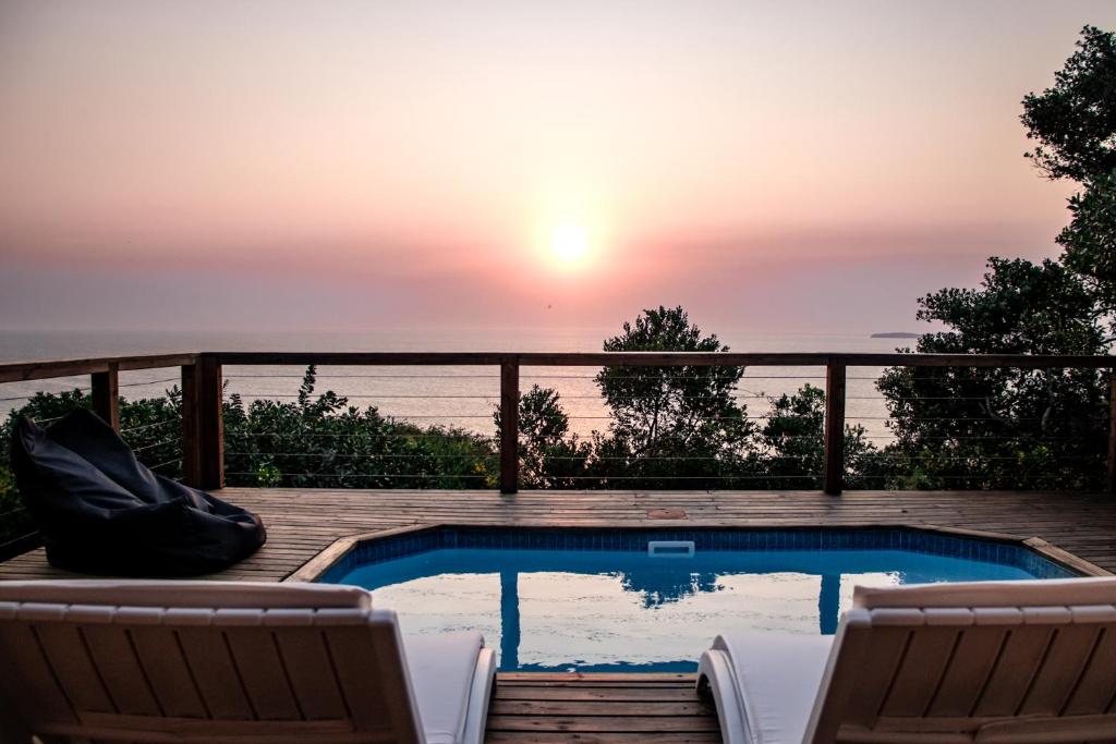 un patio con piscina, sillas y puesta de sol en The View @ Santa Maria, en Santa Maria