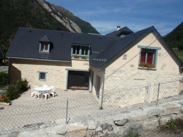 a house with a table and a fence in front of it at Gîte La Grange logement de qualité in Cauterets