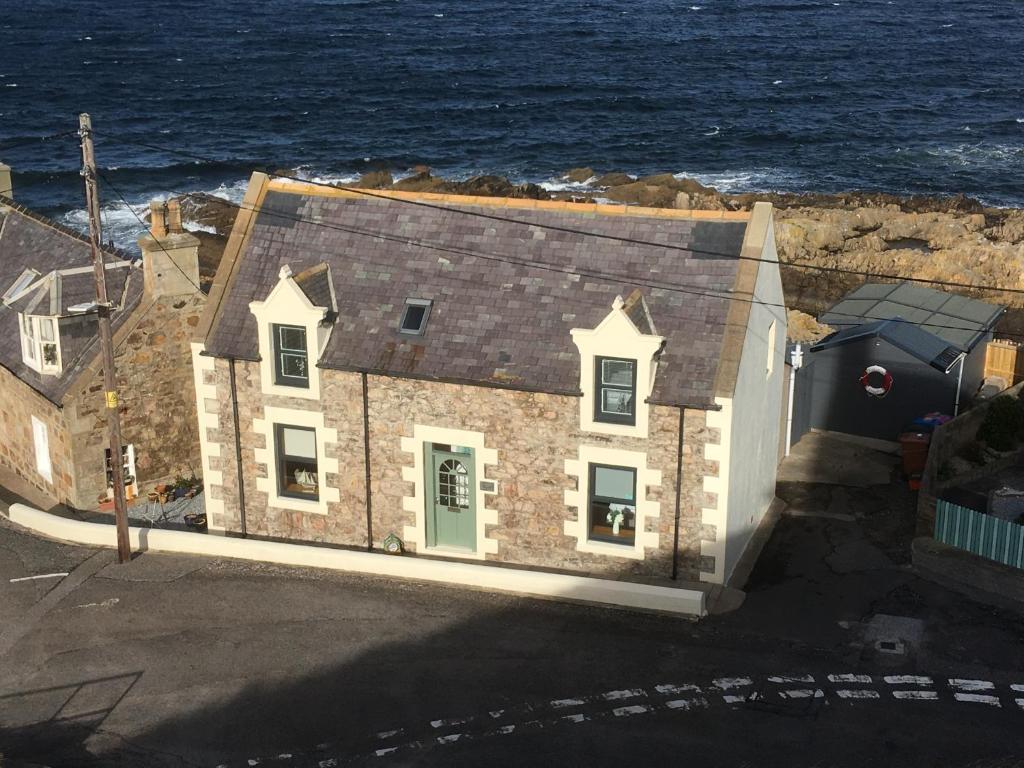 a large stone house with the ocean in the background at Seafront holiday home in Findochty in Findochty
