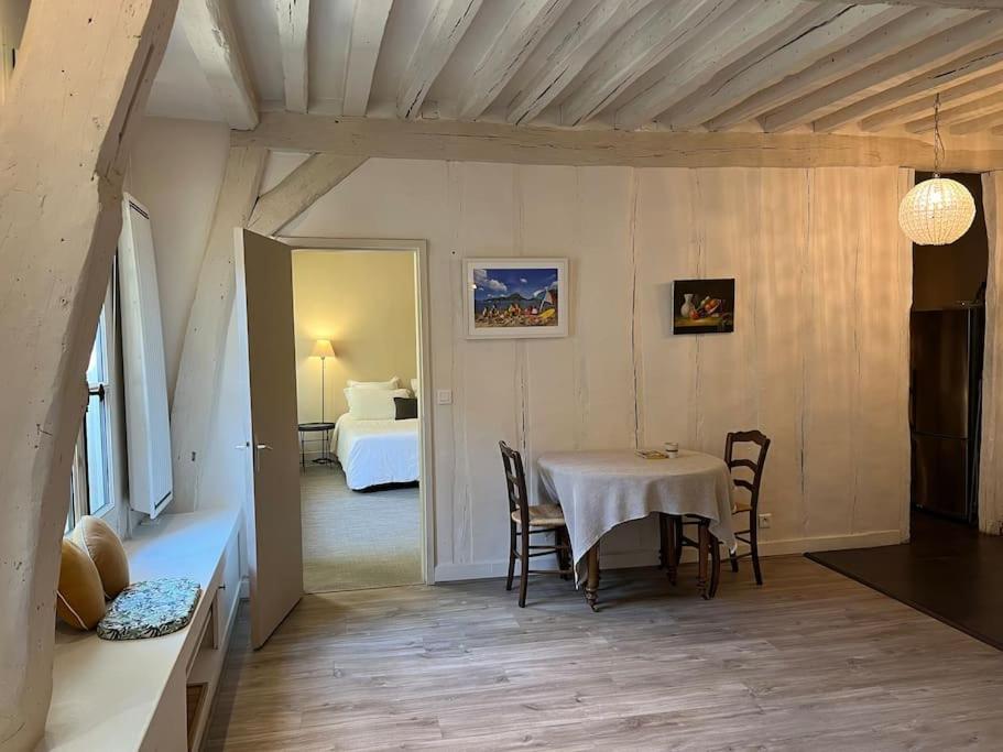 Zimmer mit einem Tisch und Stühlen sowie einem Schlafzimmer in der Unterkunft La Clé d'Anne in Saint-Germain-en-Laye