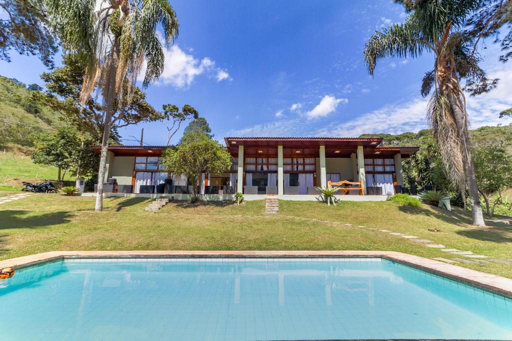 uma casa com piscina em frente a uma casa em Art Green Teresópolis em Teresópolis