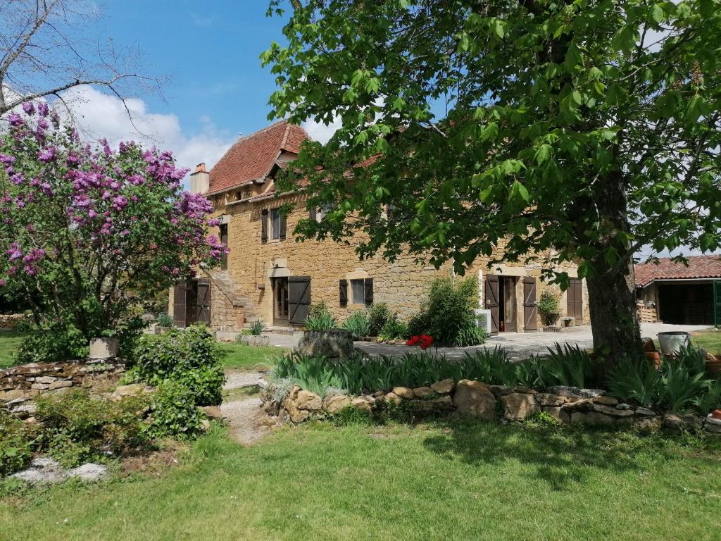 une vieille maison en pierre avec un arbre dans la cour dans l'établissement La Croisée, à Causse et Diege