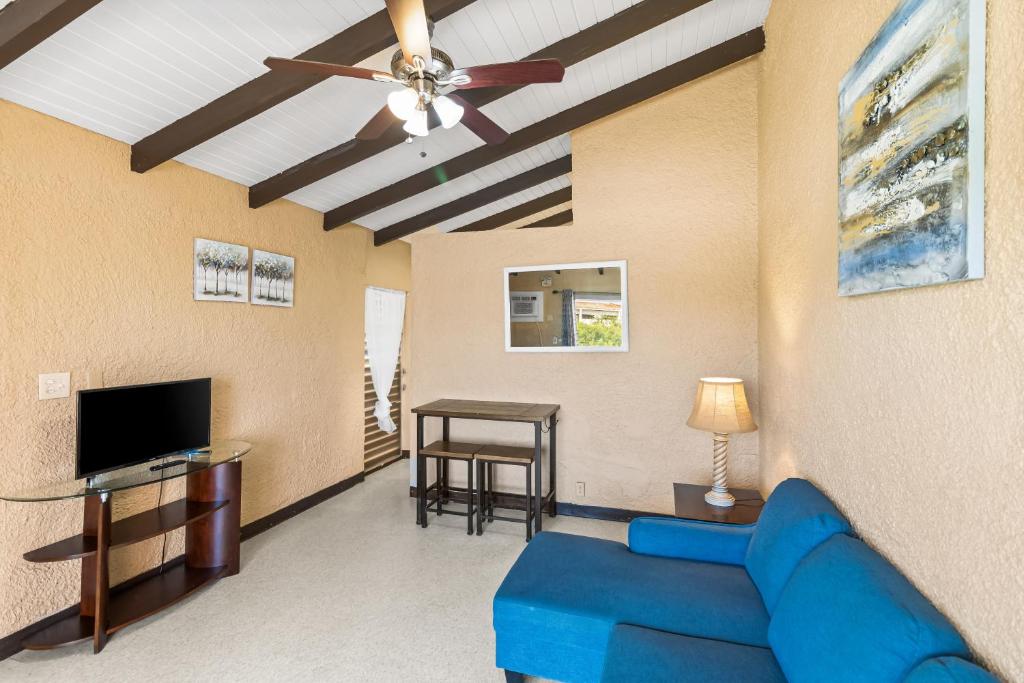 One blue Caribbean View condo في كريستيانستيد: غرفة معيشة مع أريكة زرقاء ومروحة سقف