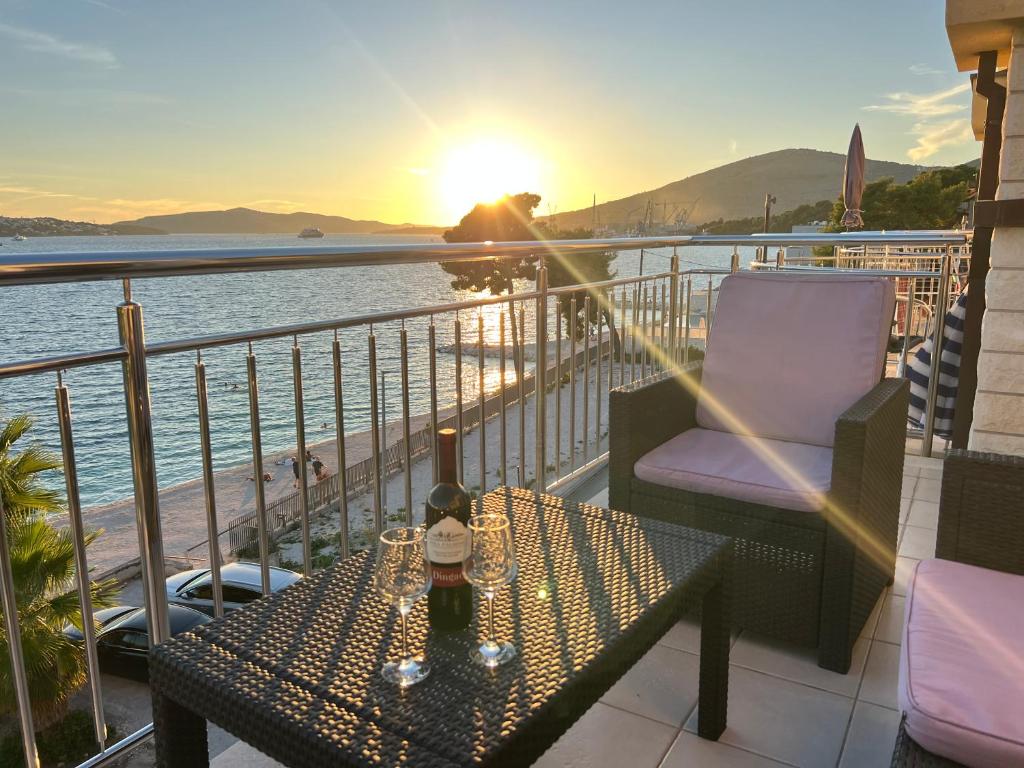 una mesa con una botella de vino en un balcón con vistas a la puesta de sol en Apartments Dado Trogir, en Trogir