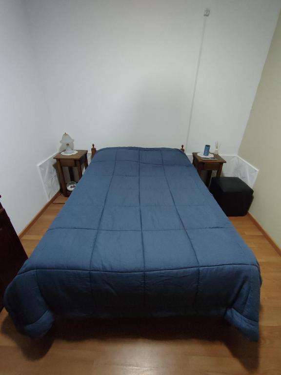 Una gran cama azul en una habitación con suelo de madera. en Depto Oro Verde en Oro Verde