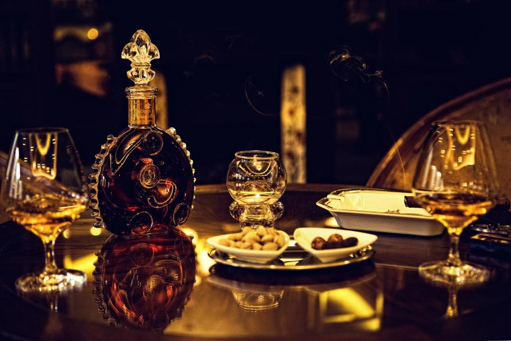 a bottle on a table with glasses and a plate of food at Retro Riverside Wellness Resort in Karlovy Vary