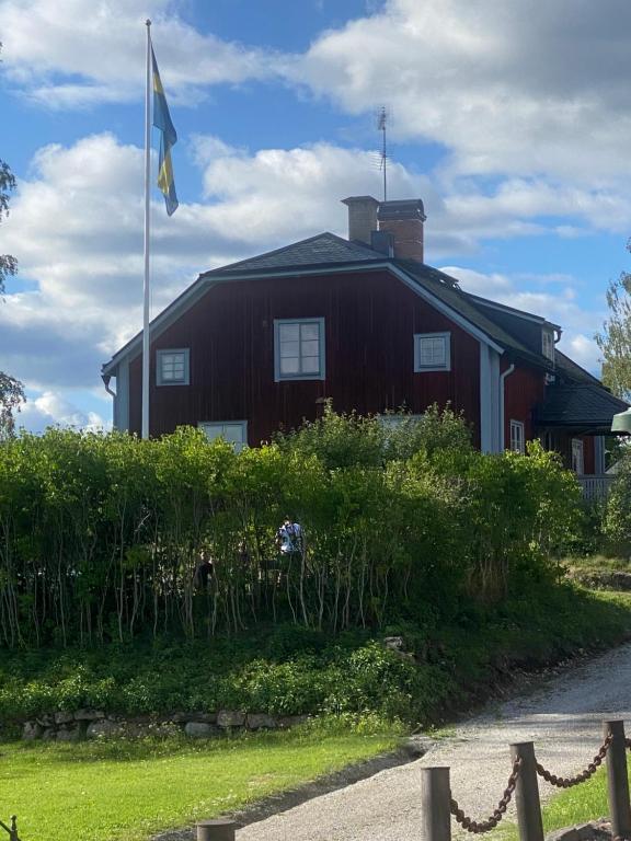 uma casa vermelha com uma bandeira em frente em Handlarens villa - Vandrarhem de luxe em Söderbärke