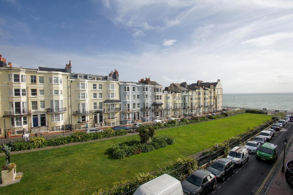 een rij huizen en auto's geparkeerd naast de oceaan bij New Steine Apartment - Sea View - by Brighton Holiday Lets in Brighton & Hove