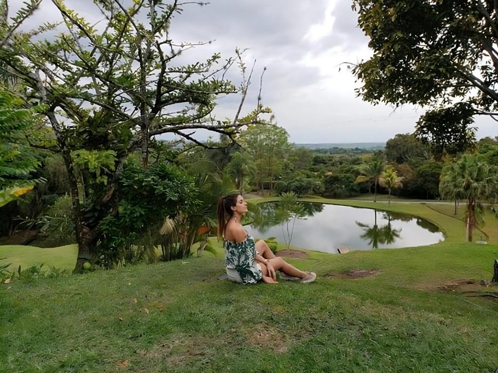 a woman sitting on the grass next to a lake at Hacienda la Romelia 