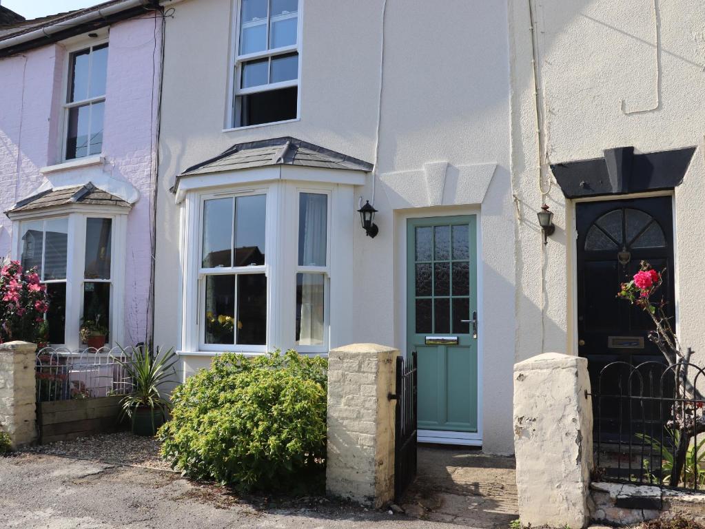 una casa blanca con una puerta azul en 46 By The Creek, en Faversham