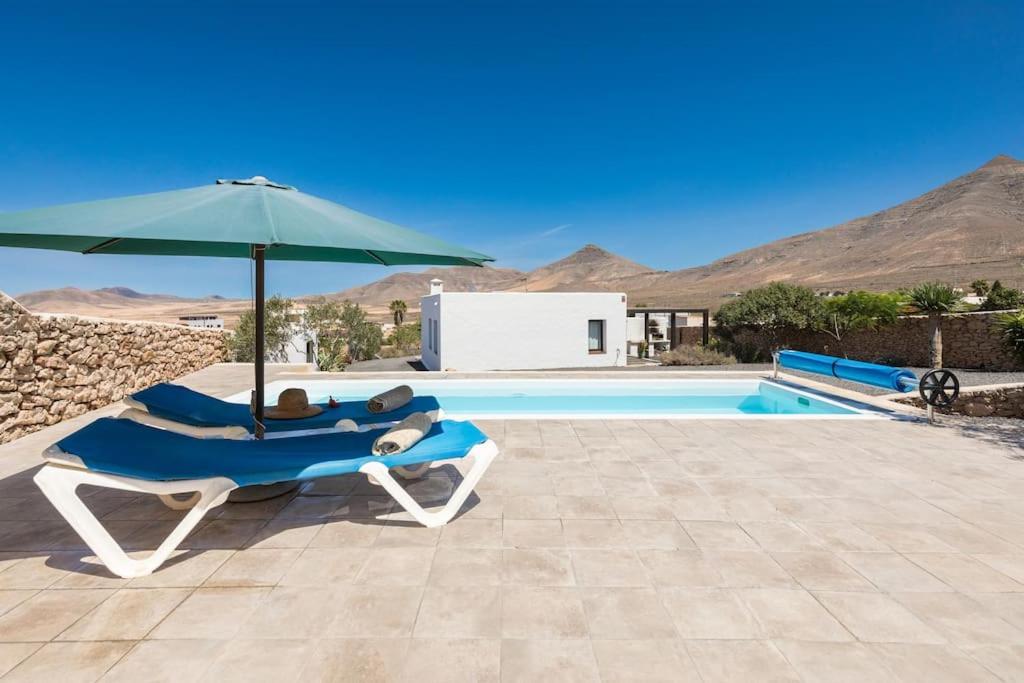 a chair and an umbrella next to a pool at Casa Marisa with Heated Pool & Garden in Tindaya