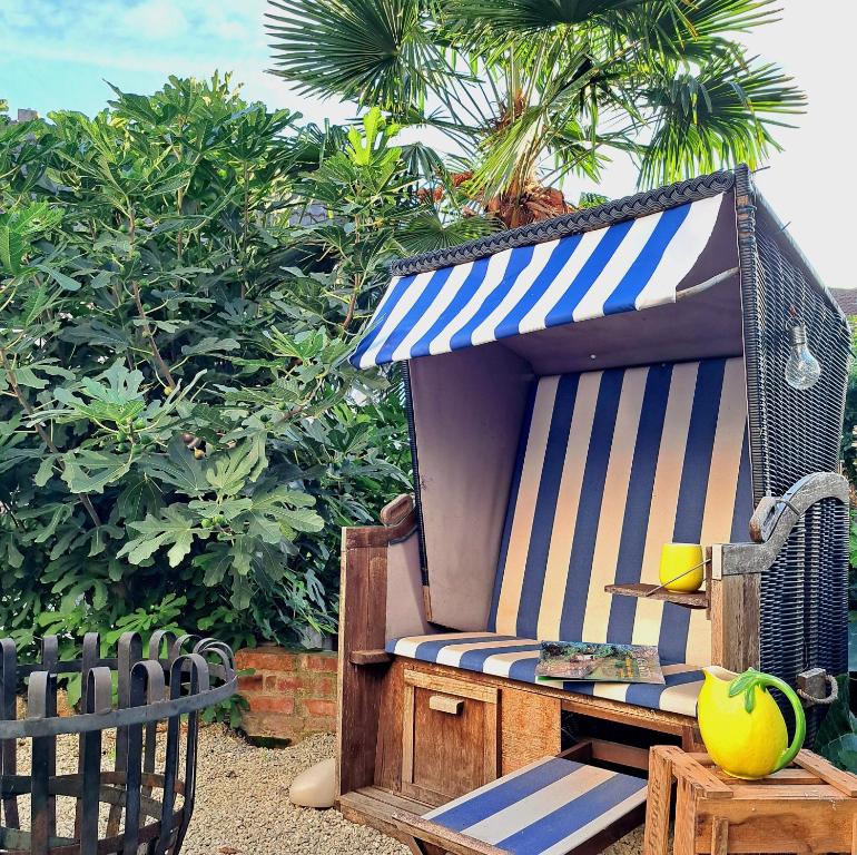 a beach chair with a striped awning on top of it at Art & Living I House and Rooms in Schoneck