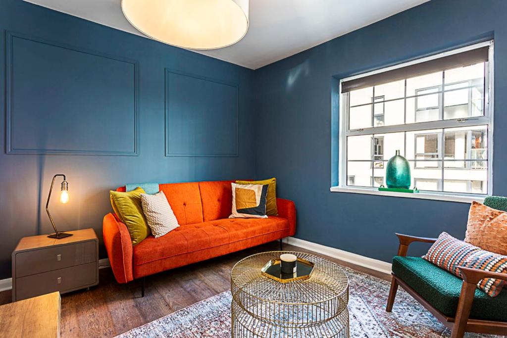 a living room with an orange couch and blue walls at Beautiful Aldgate Apartment in London