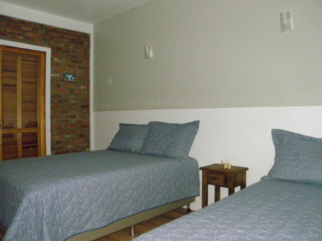Pousada Costa e Mar في Tavares: غرفة نوم بسريرين وجدار من الطوب