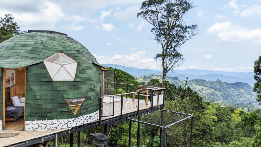 una casa en la cúpula con terraza y montañas al fondo en Glamping Reserva del Roble, en La Vega