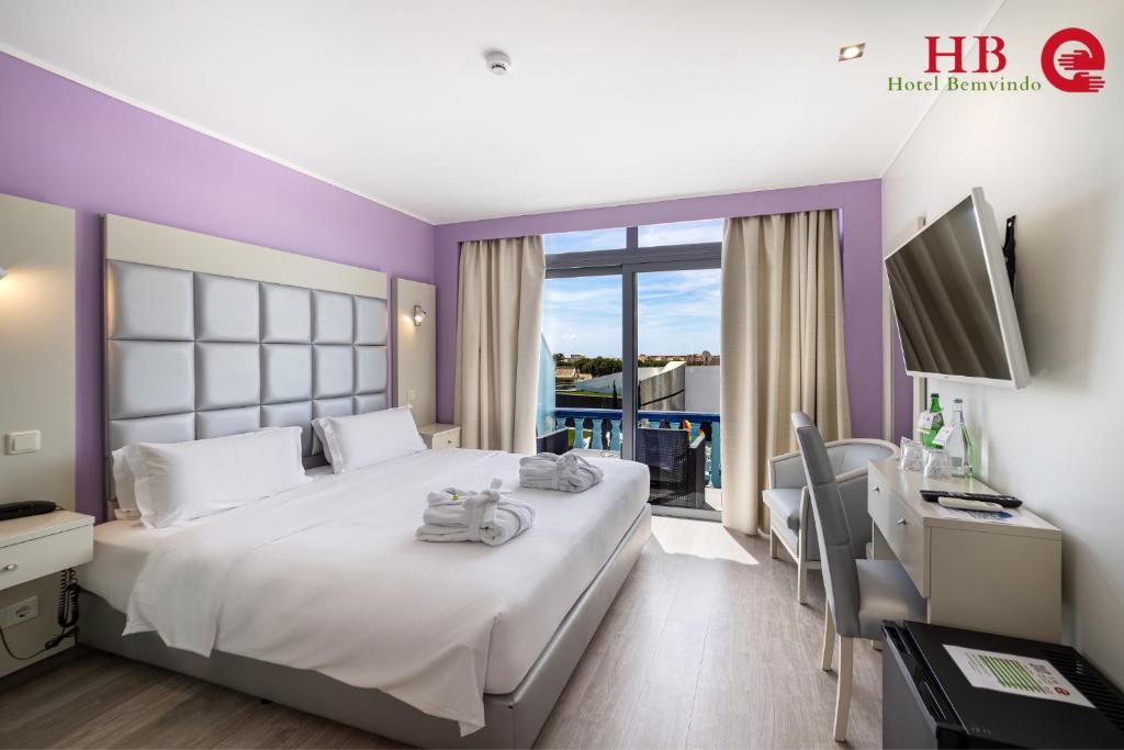 a bedroom with a bed and a desk with a computer at Urban Hotel Santa Eulalia in Albufeira