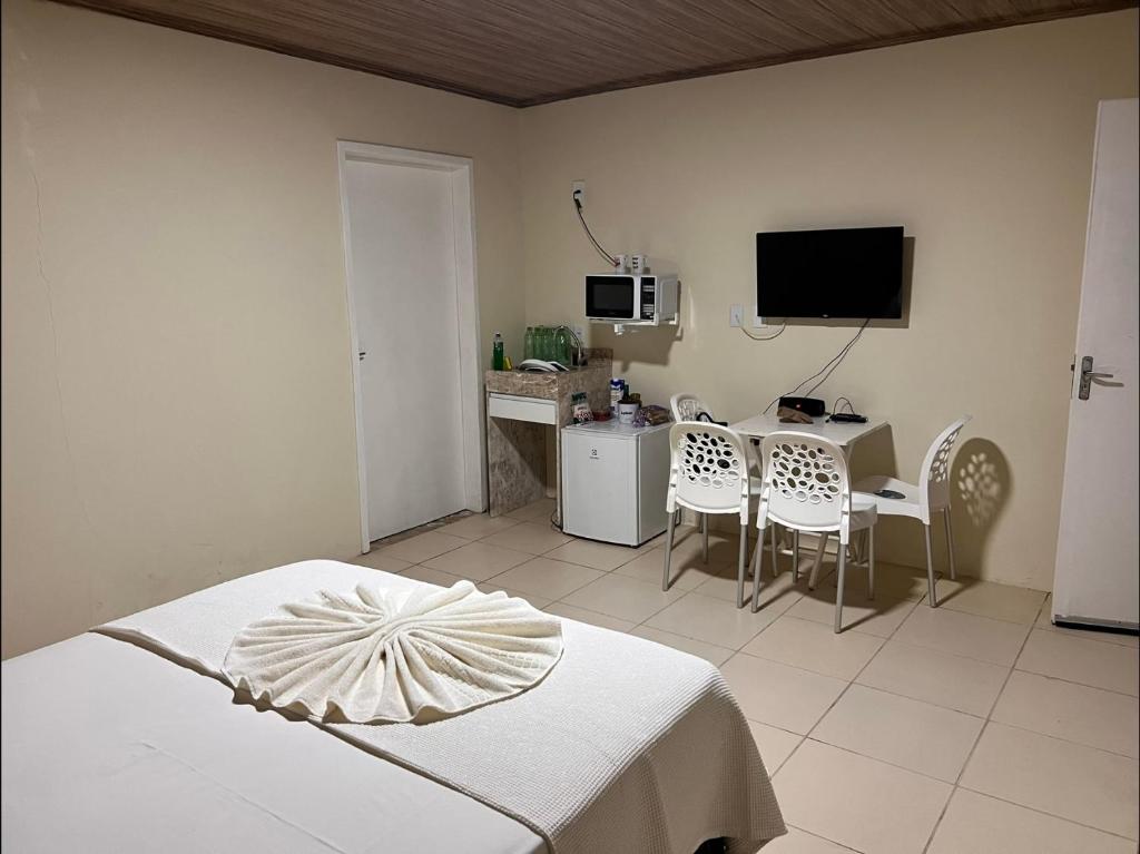 um quarto com uma cama, uma secretária e uma televisão em Flat - Condomínio Fechado - Frente Mar em Vera Cruz de Itaparica