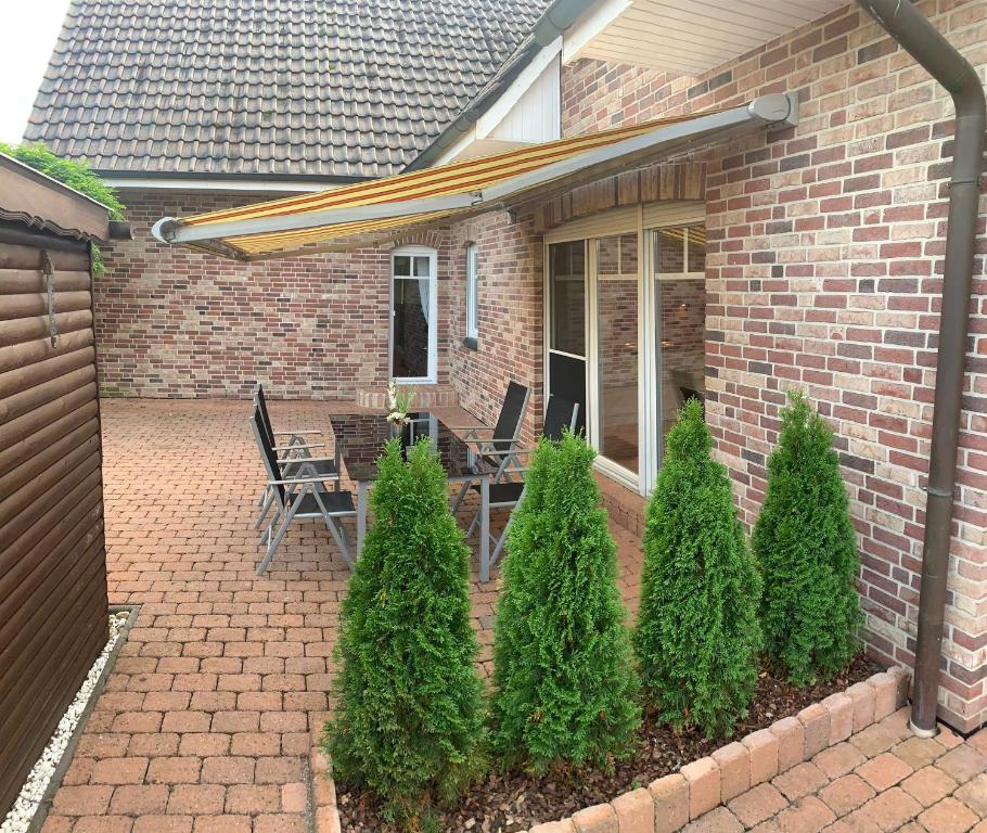 Cette maison en briques dispose d'une terrasse avec des chaises et des arbres. dans l'établissement Ferienwohnung für 4 Personen in bester Lage ca. 15 km von Bremen City, à Achim