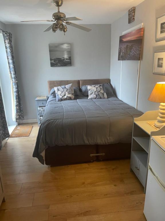 sypialnia z łóżkiem i wentylatorem sufitowym w obiekcie Cove Cott w mieście Warsash