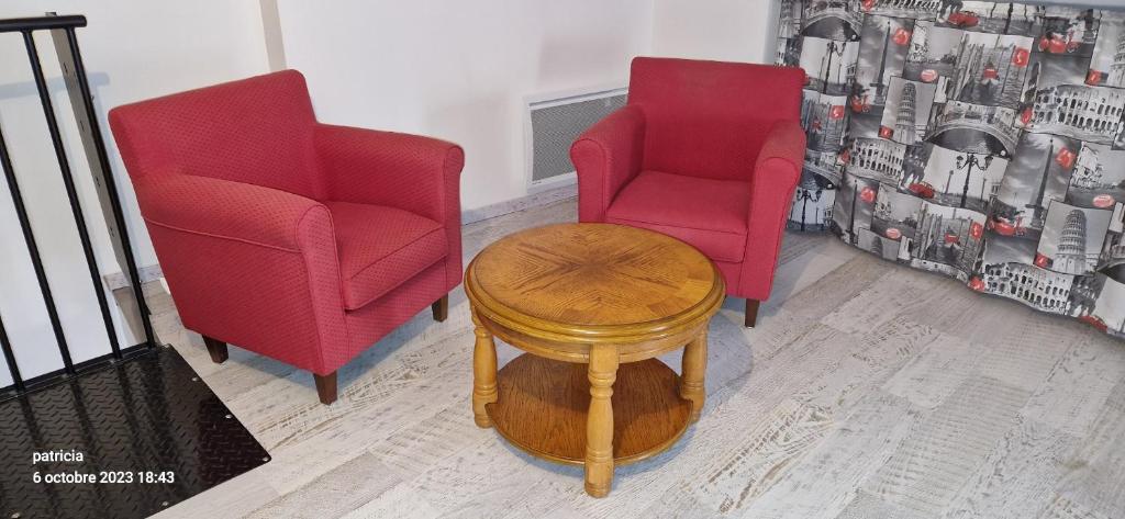 duas cadeiras vermelhas e uma mesa num quarto em l alsace em Chantonnay