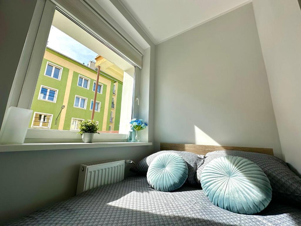 a bedroom with a bed with two pillows and a window at MMRent Citrus Room in Gdańsk