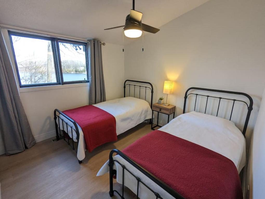 een slaapkamer met twee bedden en een raam bij Stunning lakefront 4 season cottage in PEC in Bongard