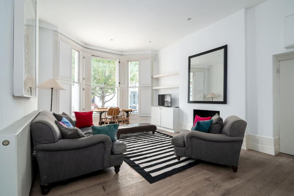 sala de estar con 2 sillas y espejo en Elegant Apartment near Portobello Road Market, en Londres