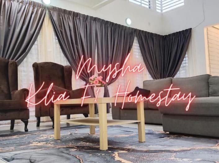 una habitación con 2 sofás y una mesa con un cartel en Mysha KLIA F1 Homestay with pool,WiFi , Netflix en Kampong Chinchang