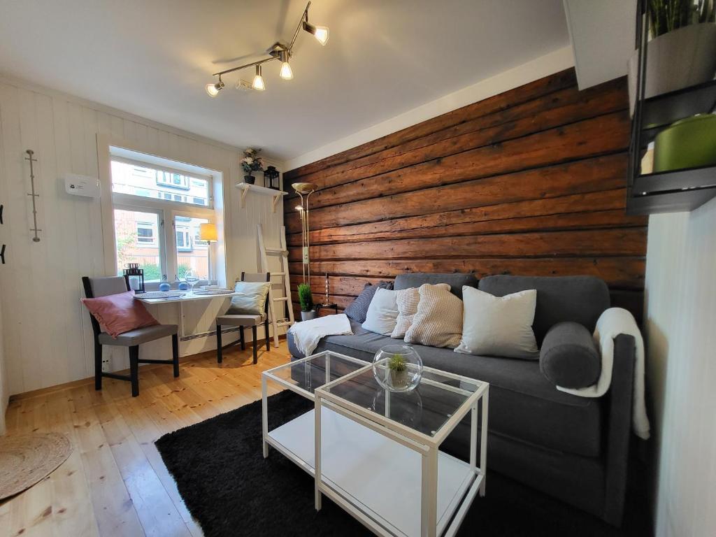 a living room with a couch and a wooden wall at Mars Modern and Cozy Apartment in the centre, Free Parking in Trondheim