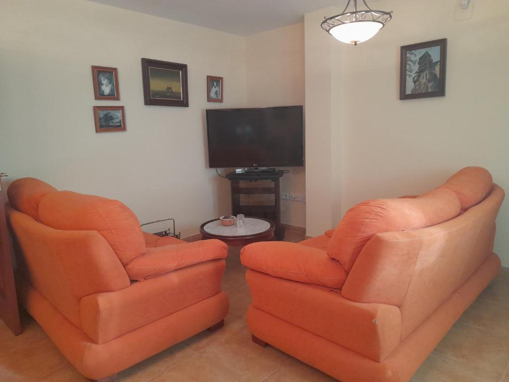 two orange chairs in a living room with a tv at La casita de carmen in Cazorla
