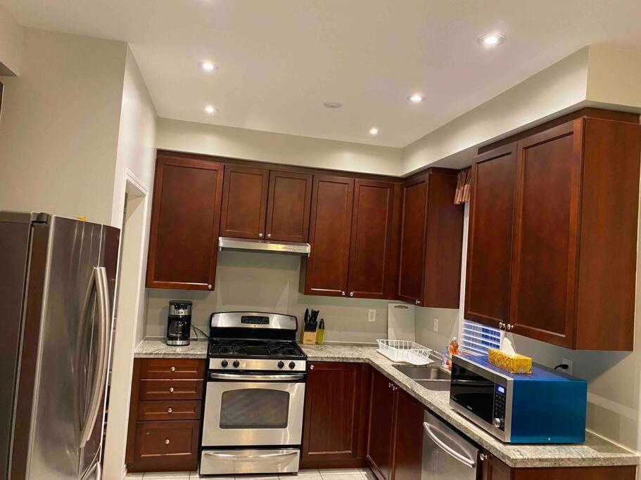 a kitchen with wooden cabinets and a stove top oven at Adorable Ajax House for Rent in Ajax