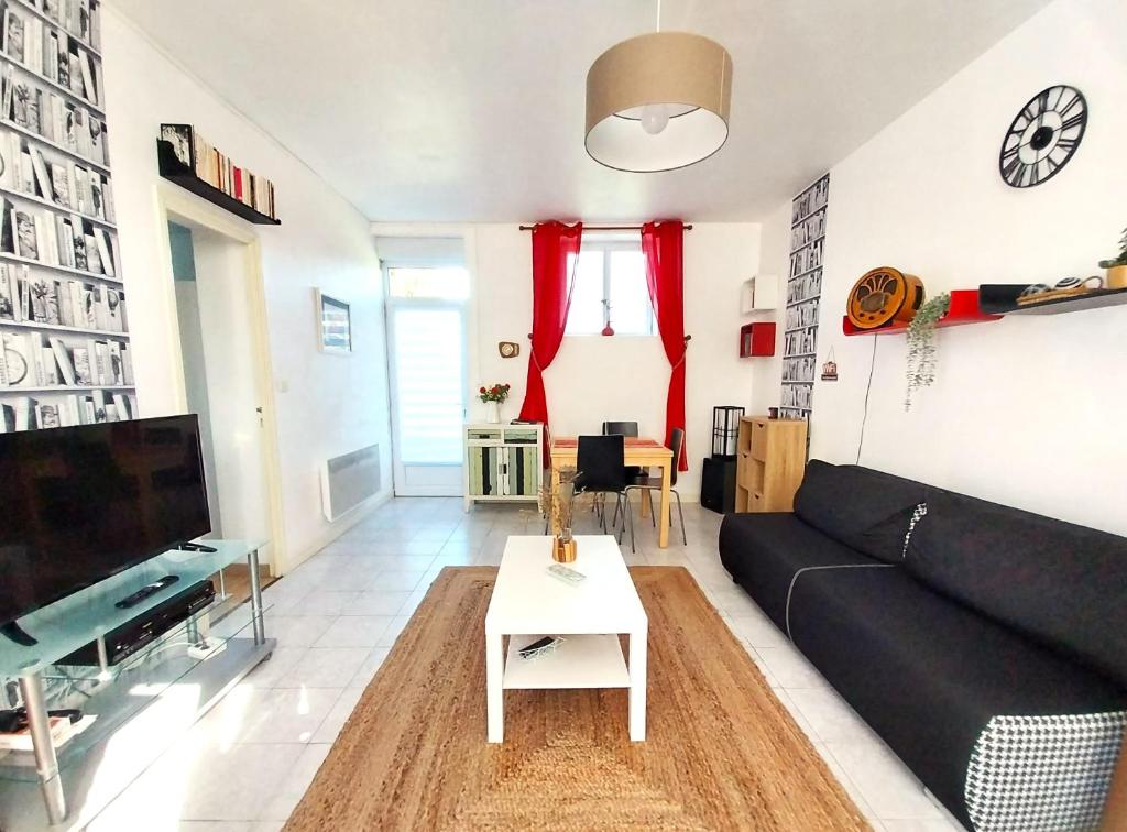 a living room with a black couch and a table at Gîte-appartement sur la Côte d'Emeraude in Beaussais sur Mer
