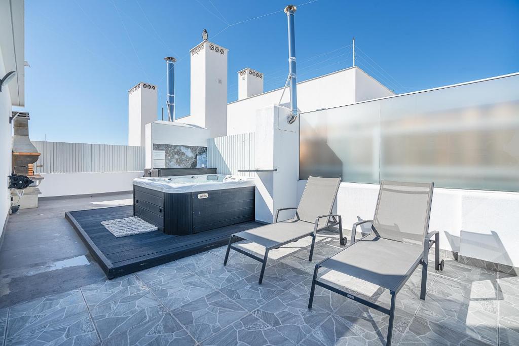 un patio avec des chaises et un bain à remous dans un bâtiment dans l'établissement New Luxury Penthouse beachfront in the Algarve, à Armação de Pêra