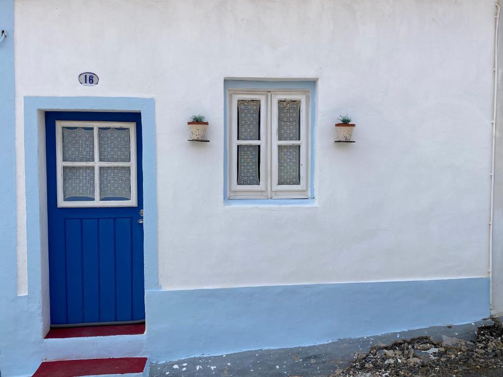 a white building with a blue door and a window at Casa na aldeia in Albernoa