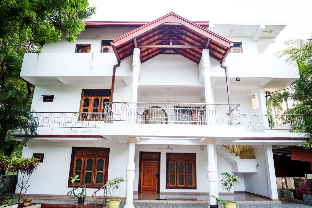 uma casa branca com portas laranja e uma varanda em SATK INN Jaffna, Kokkuvil 