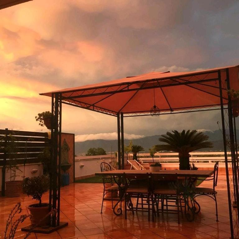a table and chairs under an umbrella on a patio at Roof Apartment in Somma Vesuviana