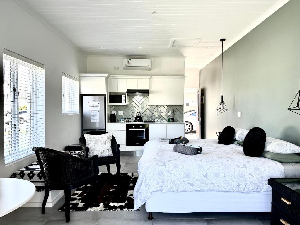 a bedroom with a large bed and a kitchen at Sea-esta in Plettenberg Bay