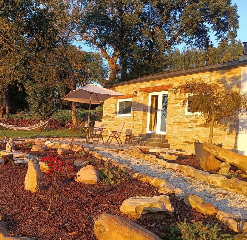 una casa de piedra con sombrilla y banco en Galician Rural Accommodation - La Casita, en Lugo