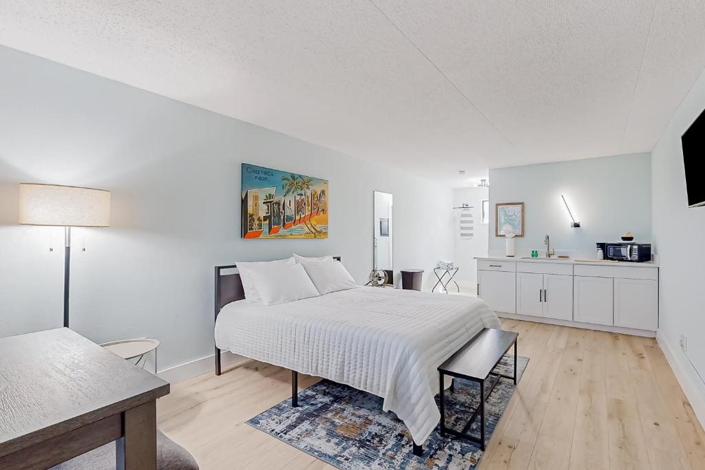 a white bedroom with a bed and a kitchen at Capri 107 in Marco Island