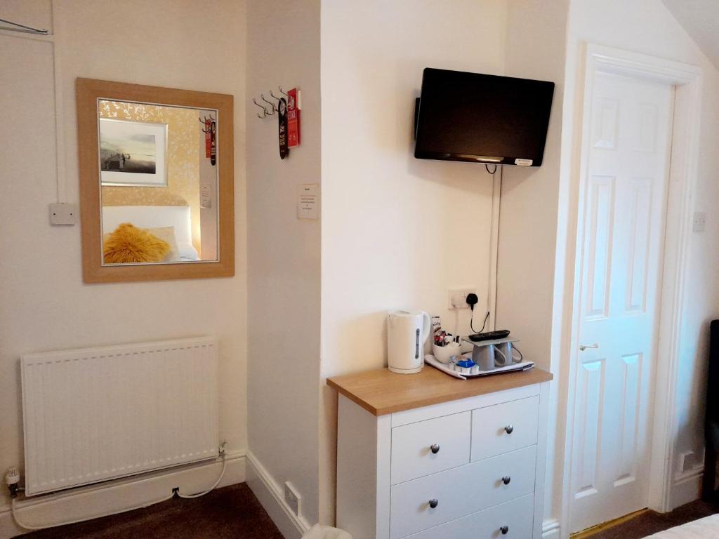 a room with a dresser and a tv on a wall at The Clovelly in Llandudno