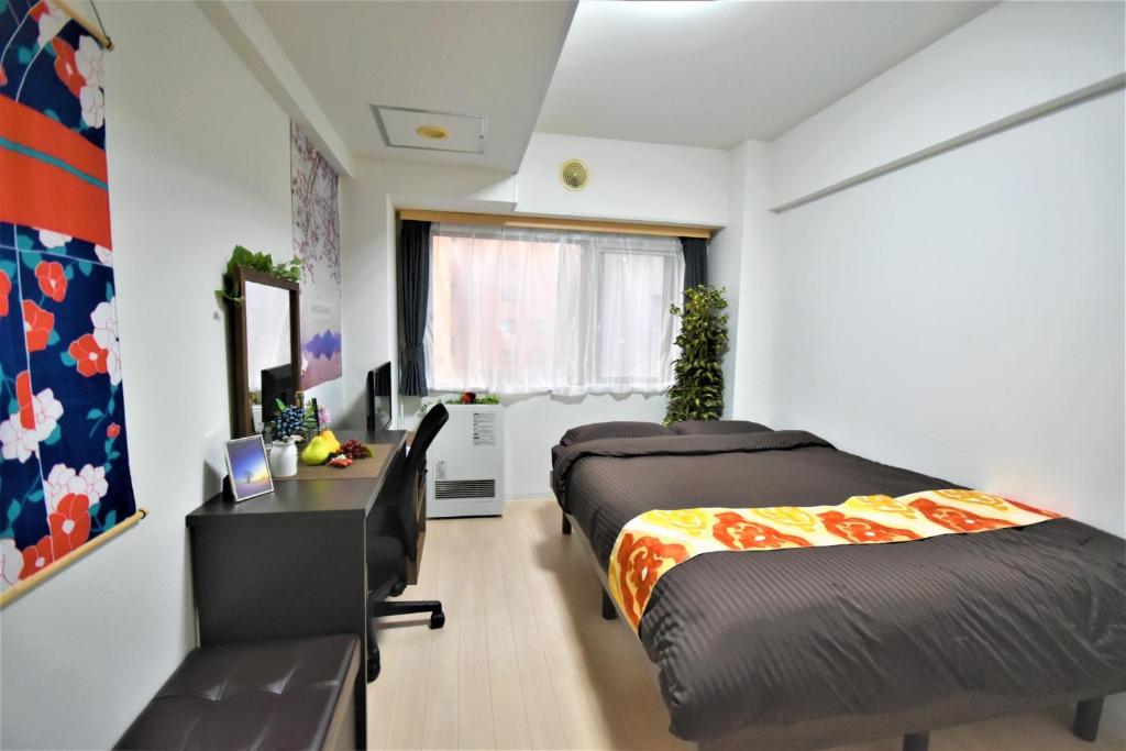 1 dormitorio con 2 camas, escritorio y escritorio en Carid Shiraishi In front of the station - Vacation STAY 15498, en Sapporo