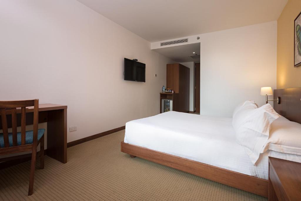 a bedroom with a bed and a desk and a television at Hotel Habitel Select in Bogotá