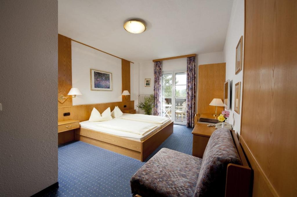 Habitación de hotel con cama y sofá en Hotel Wittelsbacher Hof en Utting am Ammersee