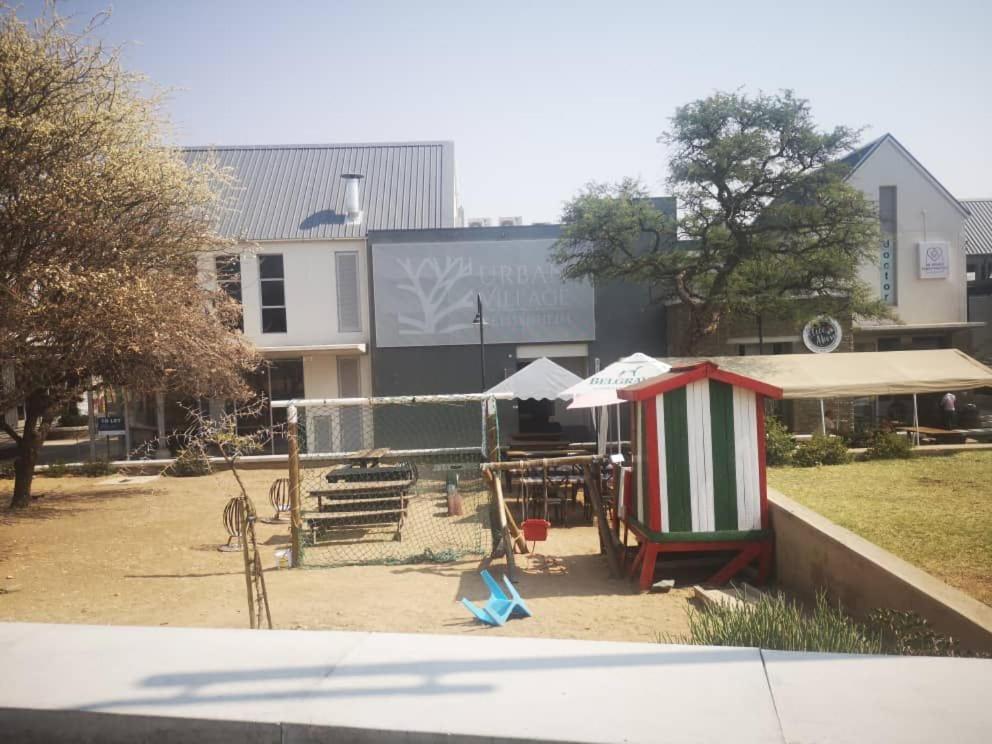 a playground with a table and umbrellas in front of a building at Cozy Stay in Windhoek