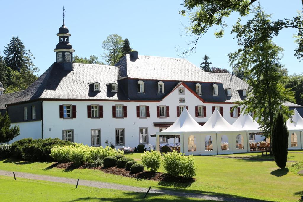 ein großes weißes Haus mit schwarzem Dach in der Unterkunft Schloss Auel Boutique Hotel & Design Golf Lodge in Lohmar